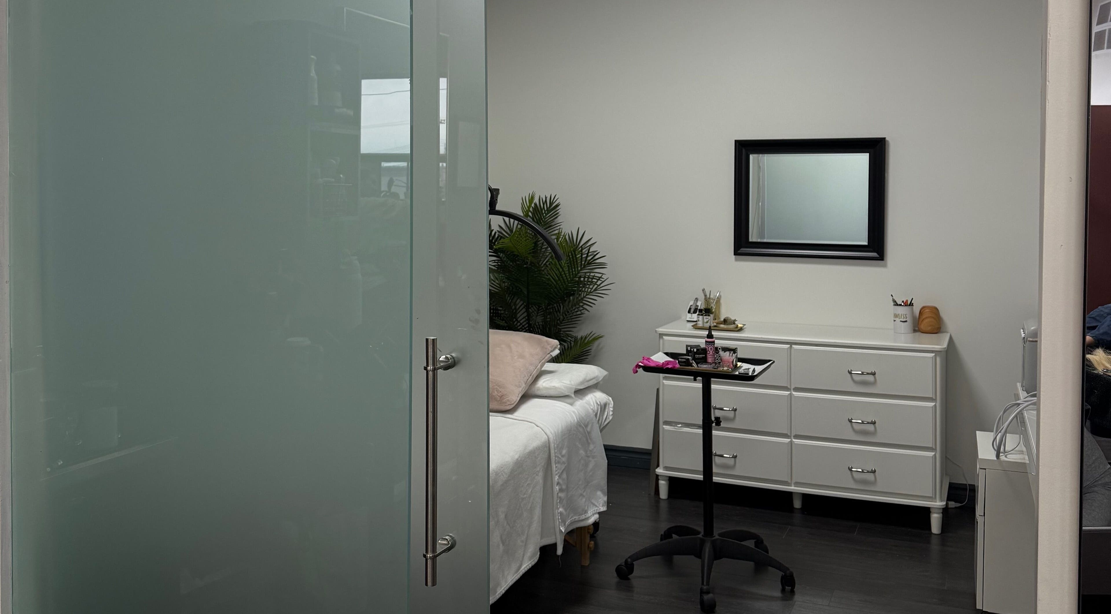 A tranquil treatment room at The Powder Room Mtl in Mont-royal, Québec, CA, featuring a bed and dresser.