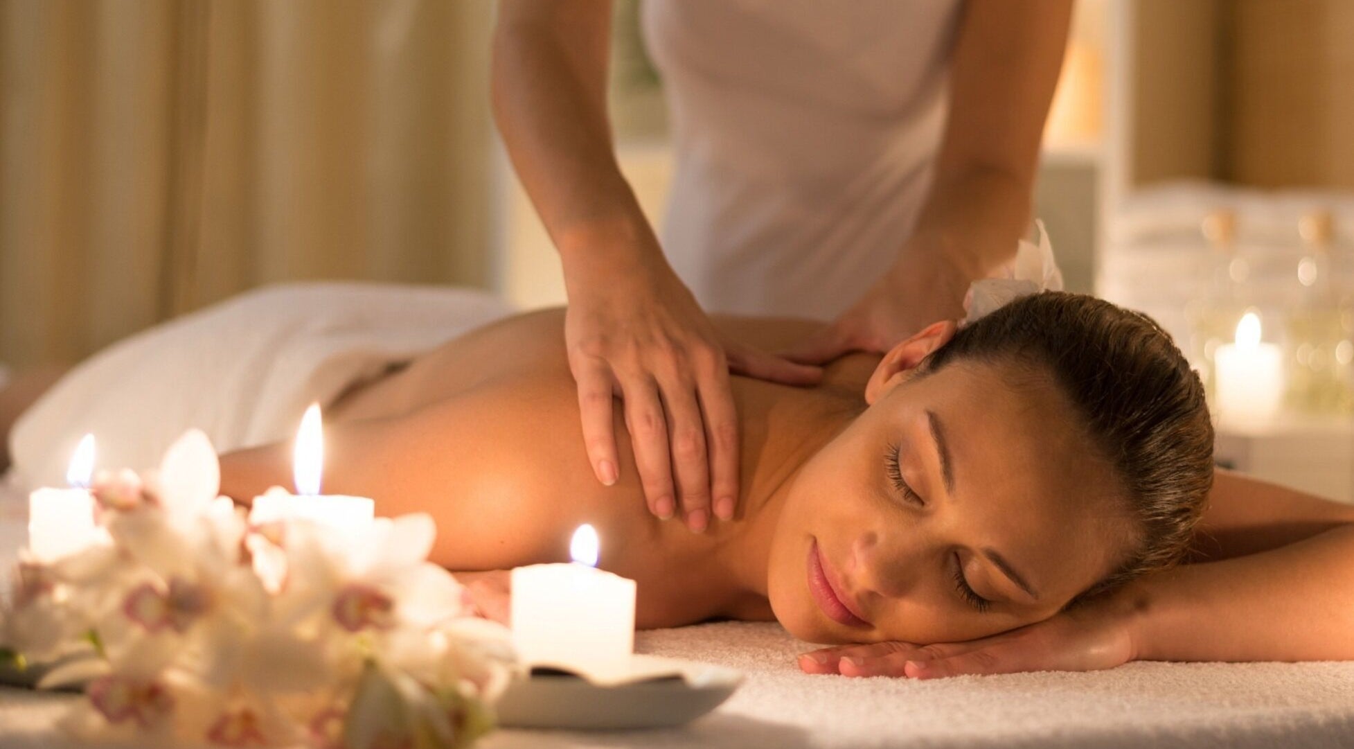 Relaxing massage at Calm Spa, Austin, Texas, US, with candles and flowers creating a peaceful ambiance.