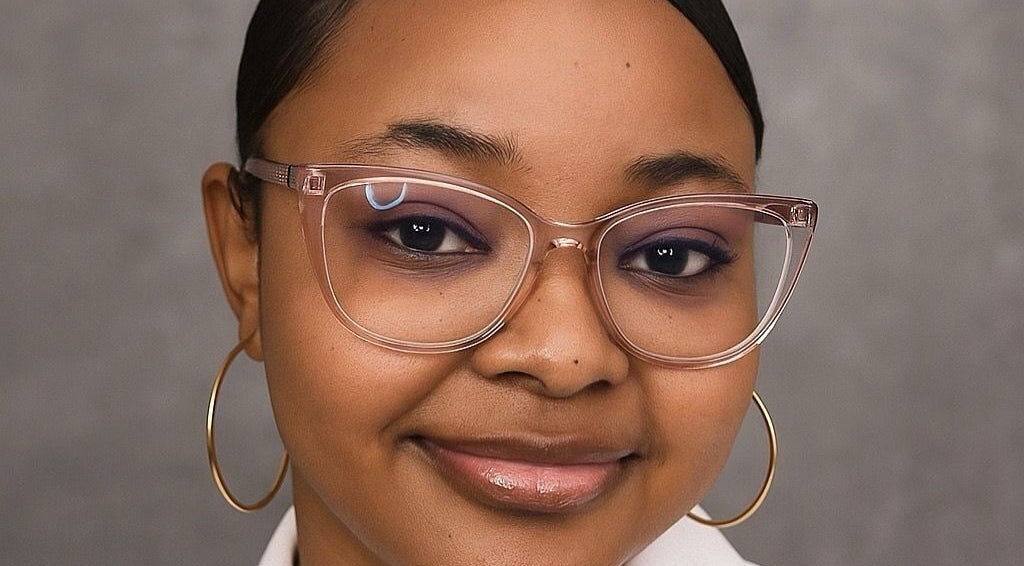 Smiling woman with chic glasses at Terina's Nail Studio, Kingstown, St. George, VC, showcasing beauty expertise.