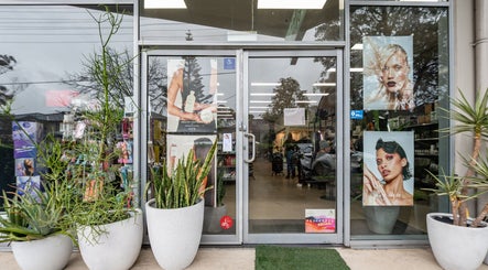 Entrance of ATSI Hair Supplies, Brookvale, NSW, showcasing stylish posters and vibrant greenery.