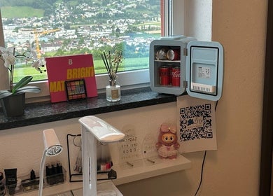 Blick auf den gepflegten Arbeitsbereich bei Lelis Nails in Vomp, Tirol, AT mit Minikühlschrank, Lampe und Dekor.