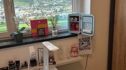 Blick auf den gepflegten Arbeitsbereich bei Lelis Nails in Vomp, Tirol, AT mit Minikühlschrank, Lampe und Dekor.