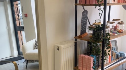 Interior of Hair by Charl in Newcastle-under-Lyme, England showing shelves with beauty products and plush seating.