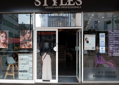Ana Wellbeing salon in Luton, England. Stylish glass facade with vibrant hair posters and modern decor.