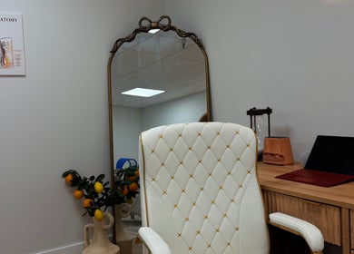 Elegant seating area at Aseel Laser Lounge, Lexington, Kentucky, US, featuring a stylish chair and mirror.