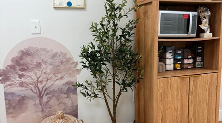 Cozy corner at Aseel Laser Lounge, Lexington. Features elegant decor with an olive tree and storage unit.