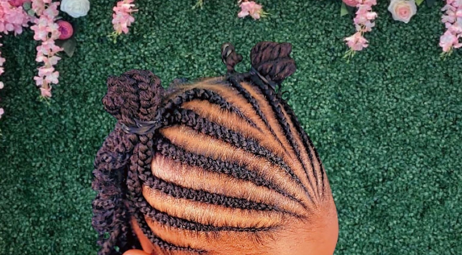 Intricate braided hairstyle with floral backdrop at The Mane & Tame Haven, Dieppe Bay, KN.