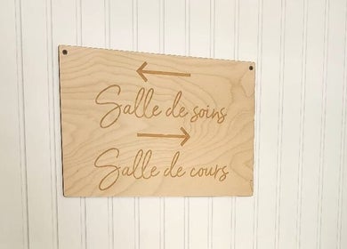 Wooden directional sign at Maison Rustik, Sainte-thérèse, Québec, CA, highlighting treatment and course rooms.