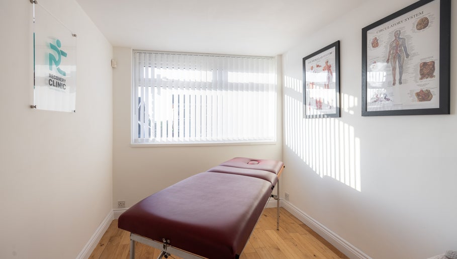 Calm treatment room at Recovery Clinic, Winlaton, England, GB, with massage table and anatomical charts.