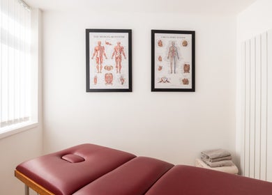 Therapy room at Recovery Clinic in Winlaton, England featuring a massage table and anatomy posters.