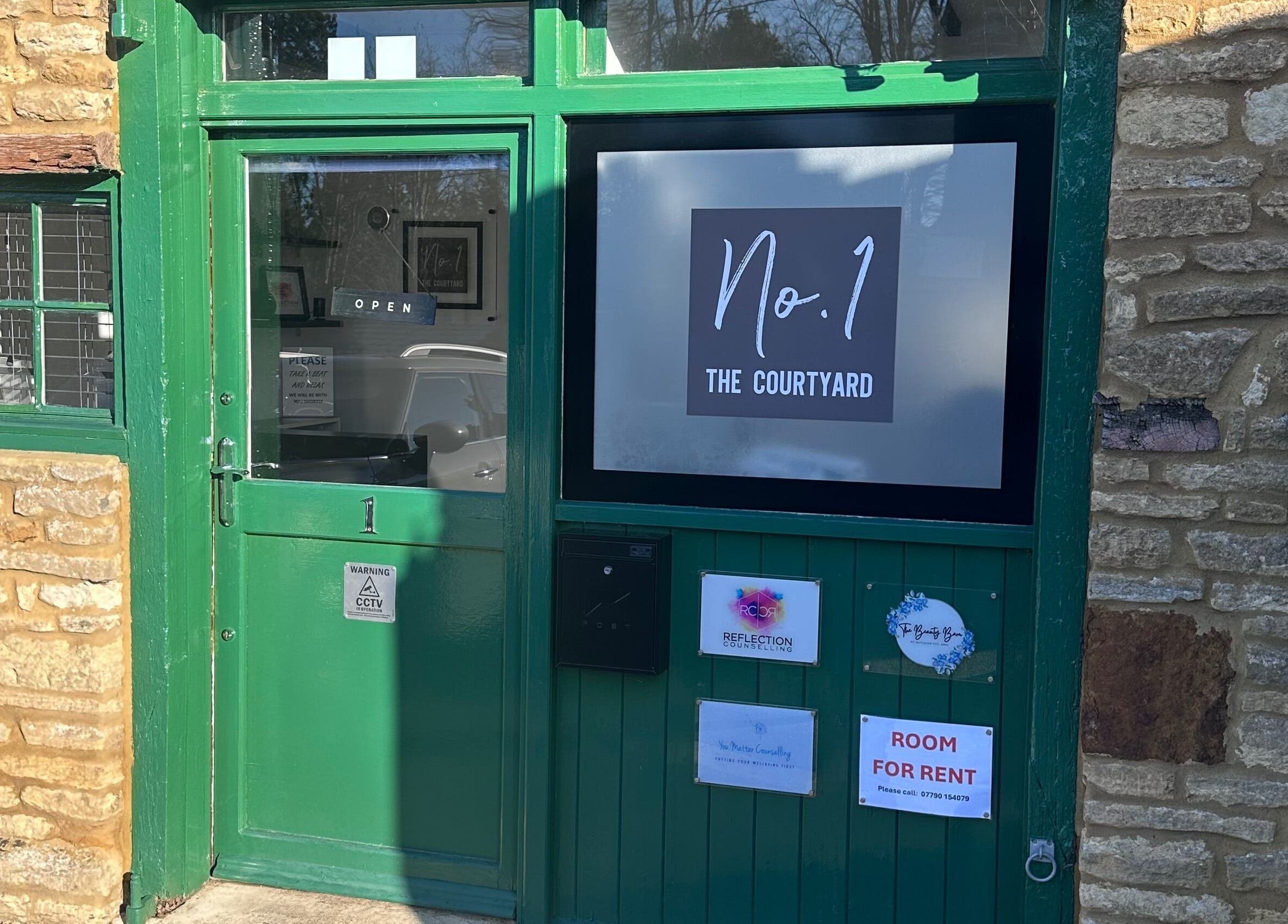 Entrance of BEAUTY CULT at No. 1 The Courtyard, Wellingborough, England, GB with a green door and brick facade.