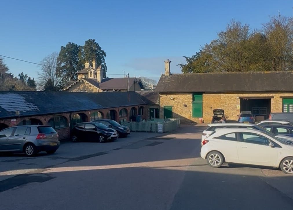 Charming courtyard at BEAUTY CULT, Wellingborough, England, GB with parked cars and rustic architecture.