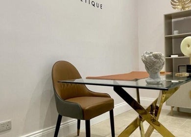 Elegant workspace at Finesse Face™️, Molesey, England, GB, showcasing a chic chair and decorative art pieces.