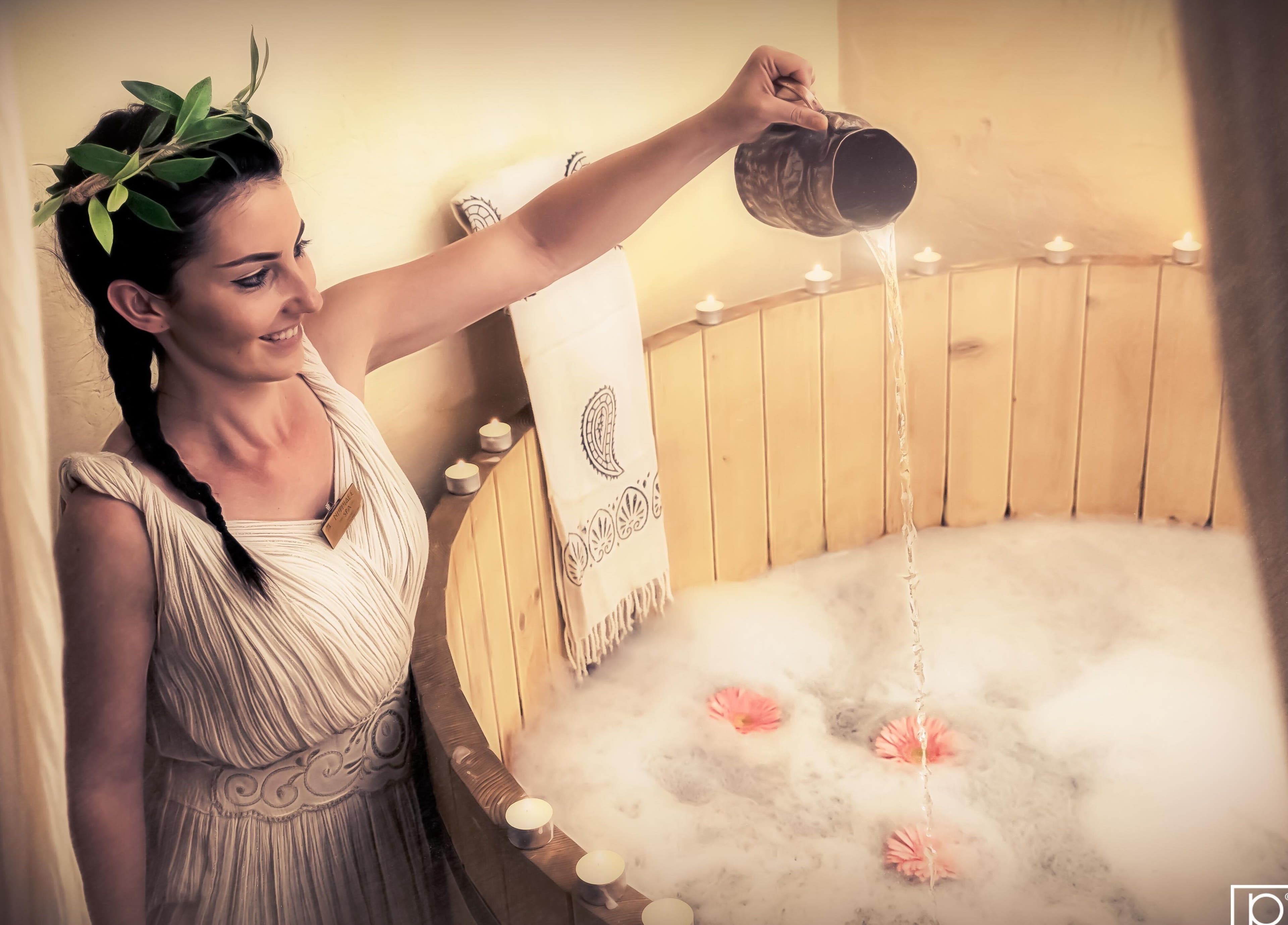 Γυναίκα ντυμένη αρχαία ελληνική ενδυμασία σε ξύλινη μπανιέρα στο Niriides Spa, Αθήνα, GR.