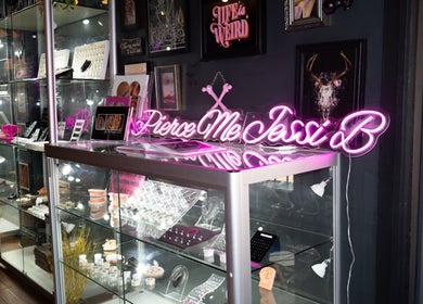 Showcase at Pierce Me Jessi B, Newark-on-Trent, England, featuring vibrant neon sign and jewelry display.