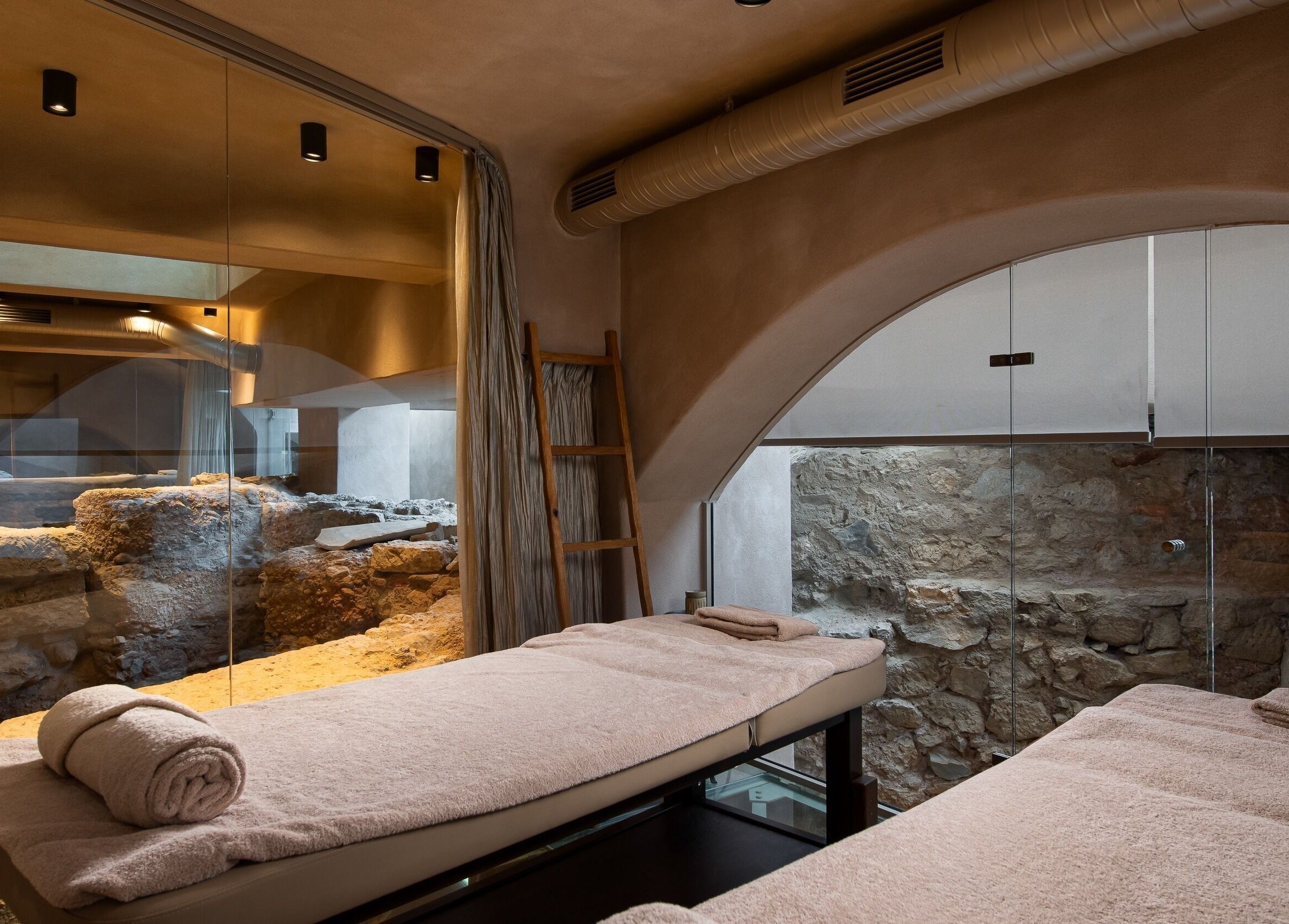 Luxurious massage room at Niche Spa 300 B.C., Athina, GR with stone walls and plush towels.
