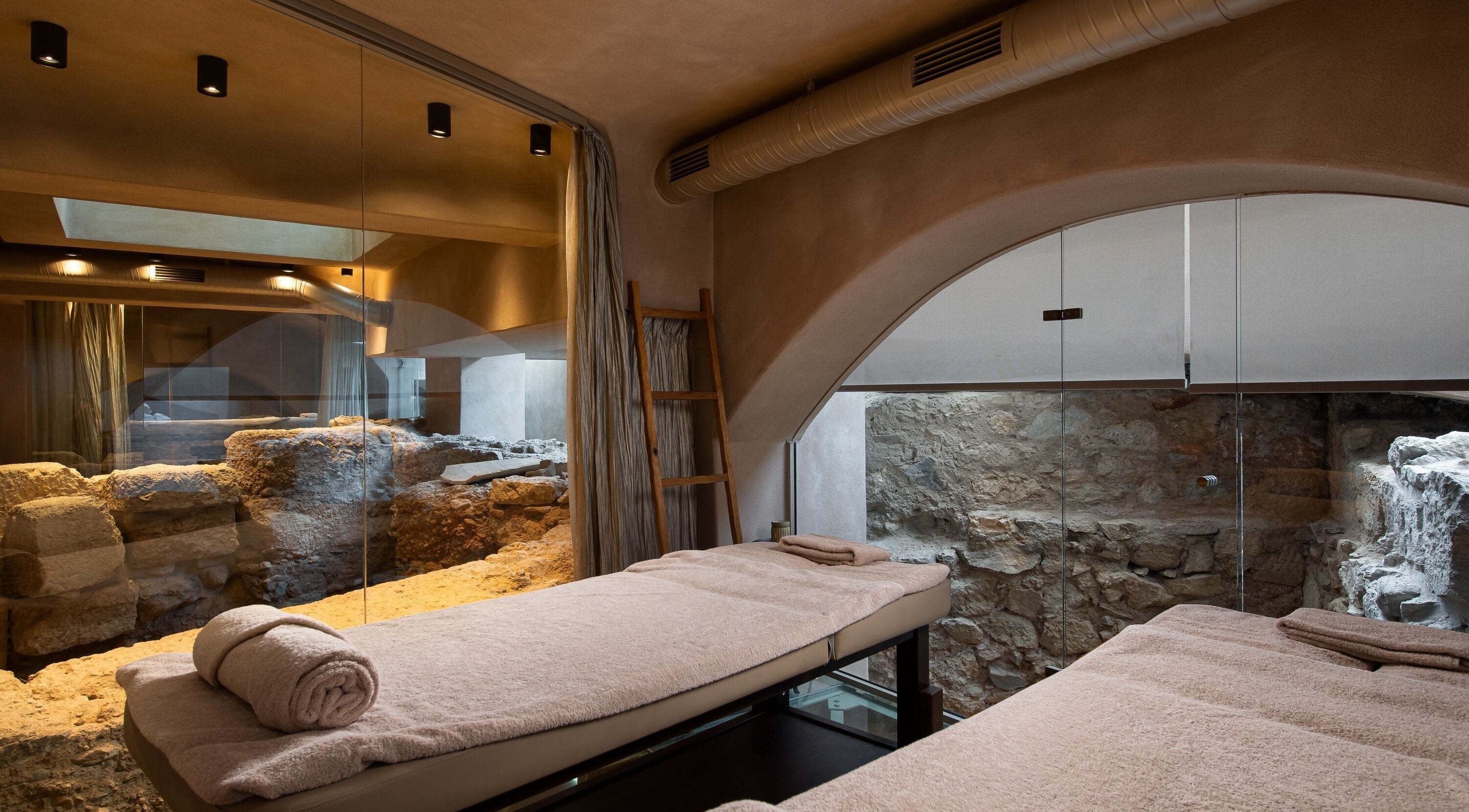 Luxurious massage room at Niche Spa 300 B.C., Athina, GR with stone walls and plush towels.