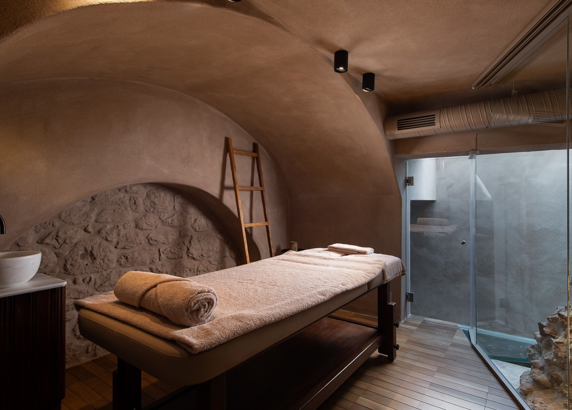 Tranquil massage room at Niche Spa 300 B.C., Athina, GR with stone walls and soft lighting.