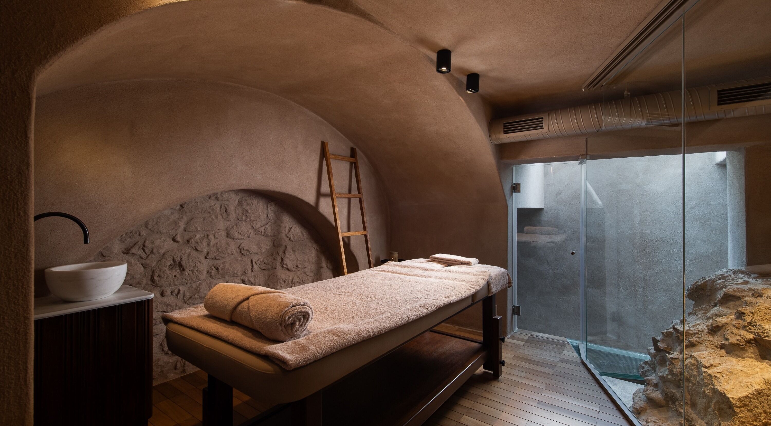 Tranquil massage room at Niche Spa 300 B.C., Athina, GR with stone walls and soft lighting.