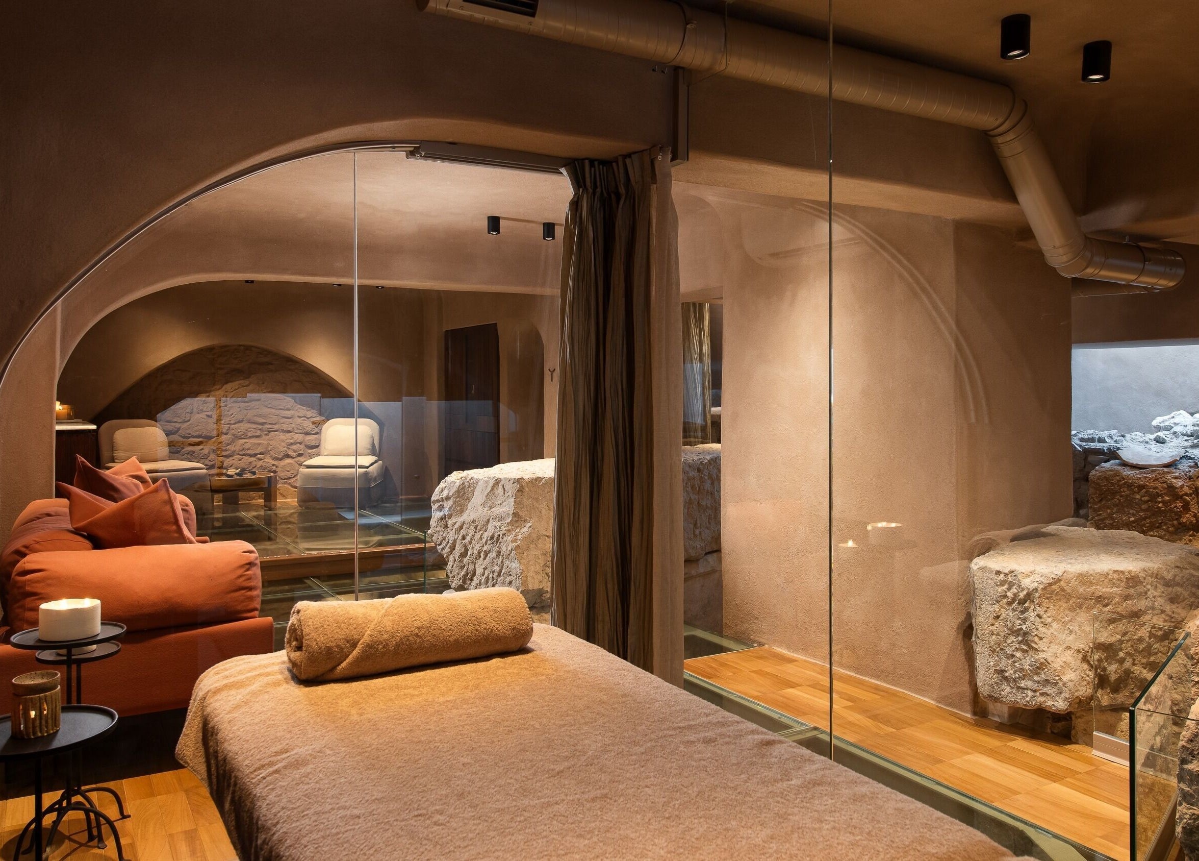Relaxing spa room at Niche Spa 300 B.C. in Athina, GR, featuring cozy seating and ancient stone decor.