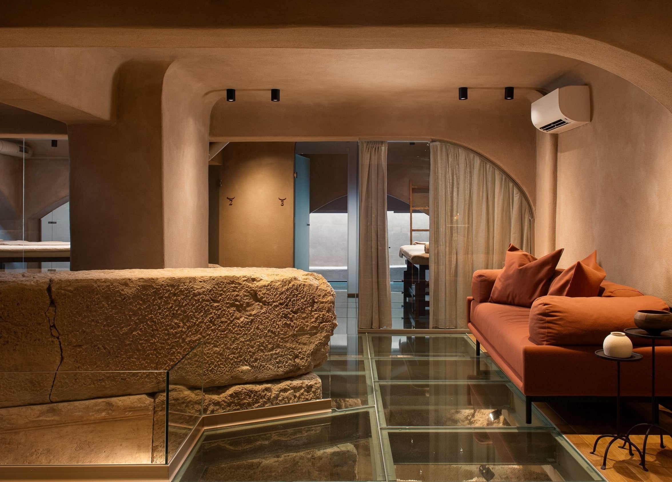 Calm relaxation area at Niche Spa 300 B.C. in Athina, GR featuring a stone wall and modern seating.