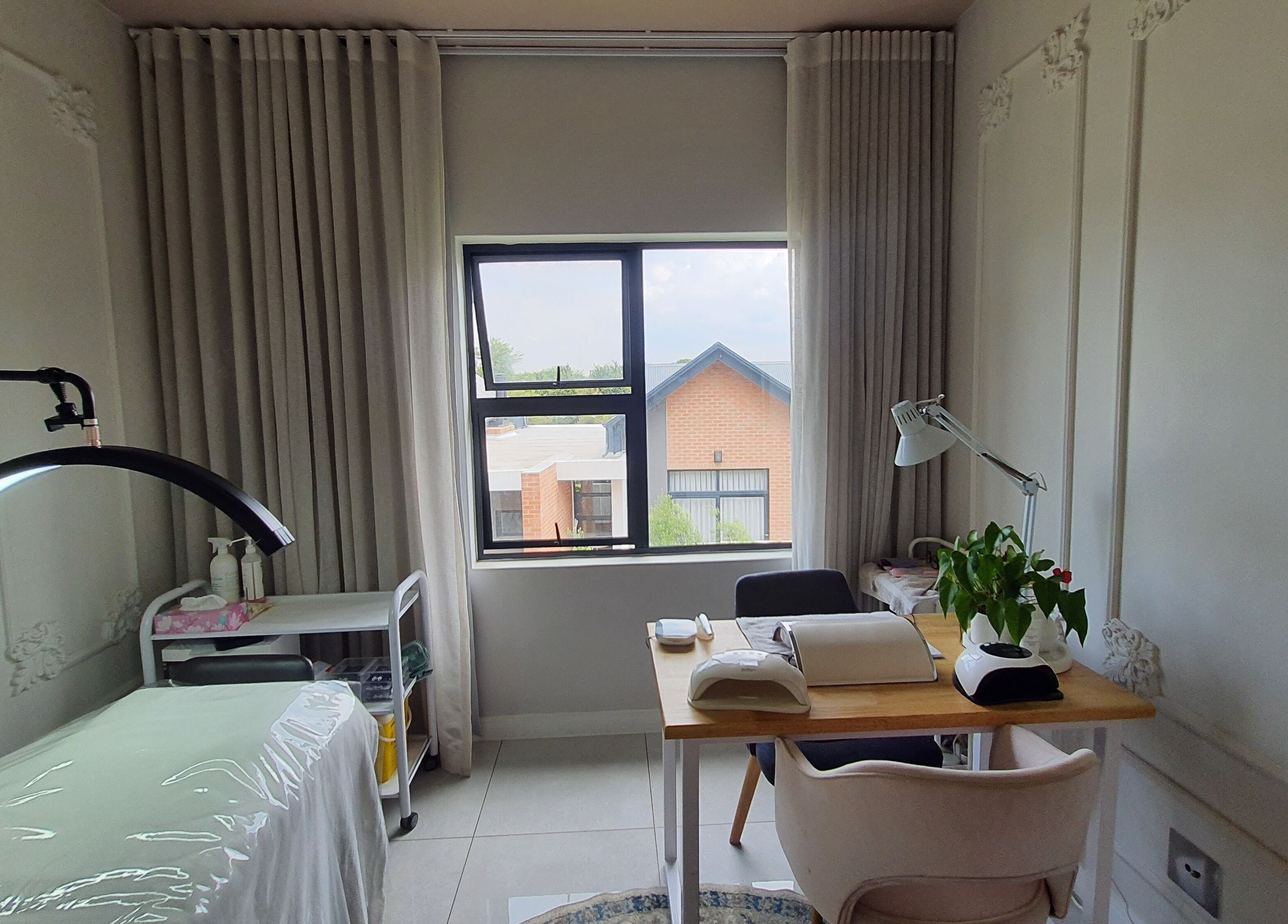 A tranquil treatment room at AesthetiDerm in Centurion, Gauteng, ZA, featuring a cozy bed and a well-lit desk.