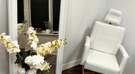 Elegant salon decor with white chair and flowers at By Frankie Zoe - Congleton (at Skin & Beauty by Sarah-Jayne), Congleton, England, GB.