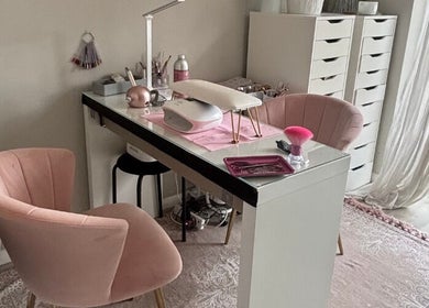Stylish nail station at Aries Nails in Hitchin, England, GB, featuring plush pink chairs and organized workspace.