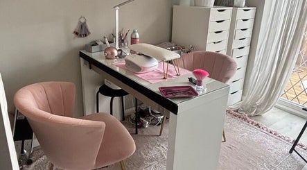 Stylish nail station at Aries Nails in Hitchin, England, GB, featuring plush pink chairs and organized workspace.