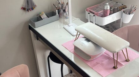 Nail station at Aries Nails, Hitchin, England, GB, featuring polish selection, lamp, and pink chair.