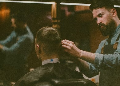 Barber at work in Barber Den, Valencia, Comunidad Valenciana, ES, crafting a modern haircut.