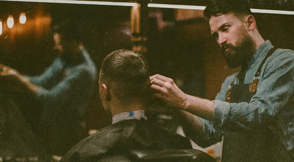 Barber at work in Barber Den, Valencia, Comunidad Valenciana, ES, crafting a modern haircut.