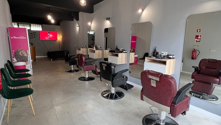 Interior moderno do Pixel Barbershop em Lisboa, Lisboa, PT, com cadeiras vermelhas e espelhos elegantes.