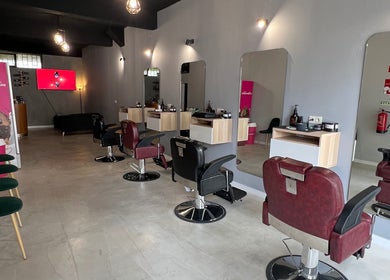 Interior moderno do Pixel Barbershop em Lisboa, Lisboa, PT, com cadeiras vermelhas e espelhos elegantes.