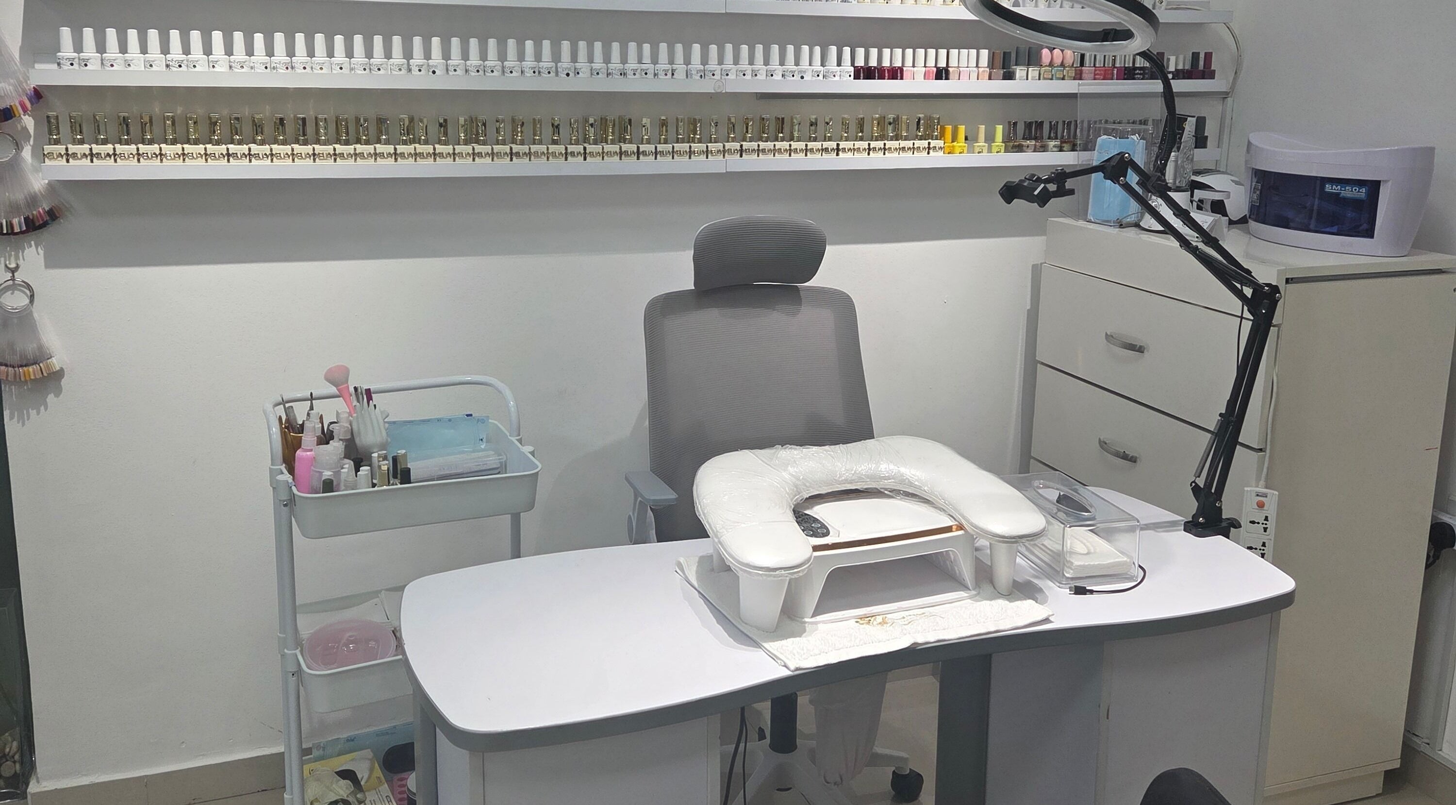 Nail station at Aljamal Almithali Beauty Salon in Ajman, AE, showcasing tools and vibrant polish selection.