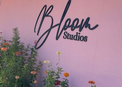 Colorful flowers outside Elite Esthetics by Dalal, Lodi, California, US, with studio sign on a pink wall.