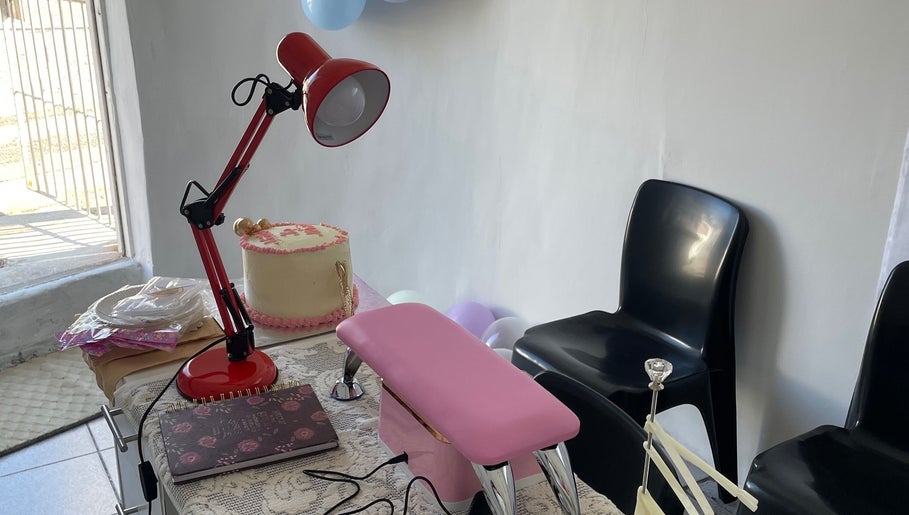 Nail station setup at Nailed By Ndasi, Gqeberha, Eastern Cape, ZA with a red lamp and pink armrest.