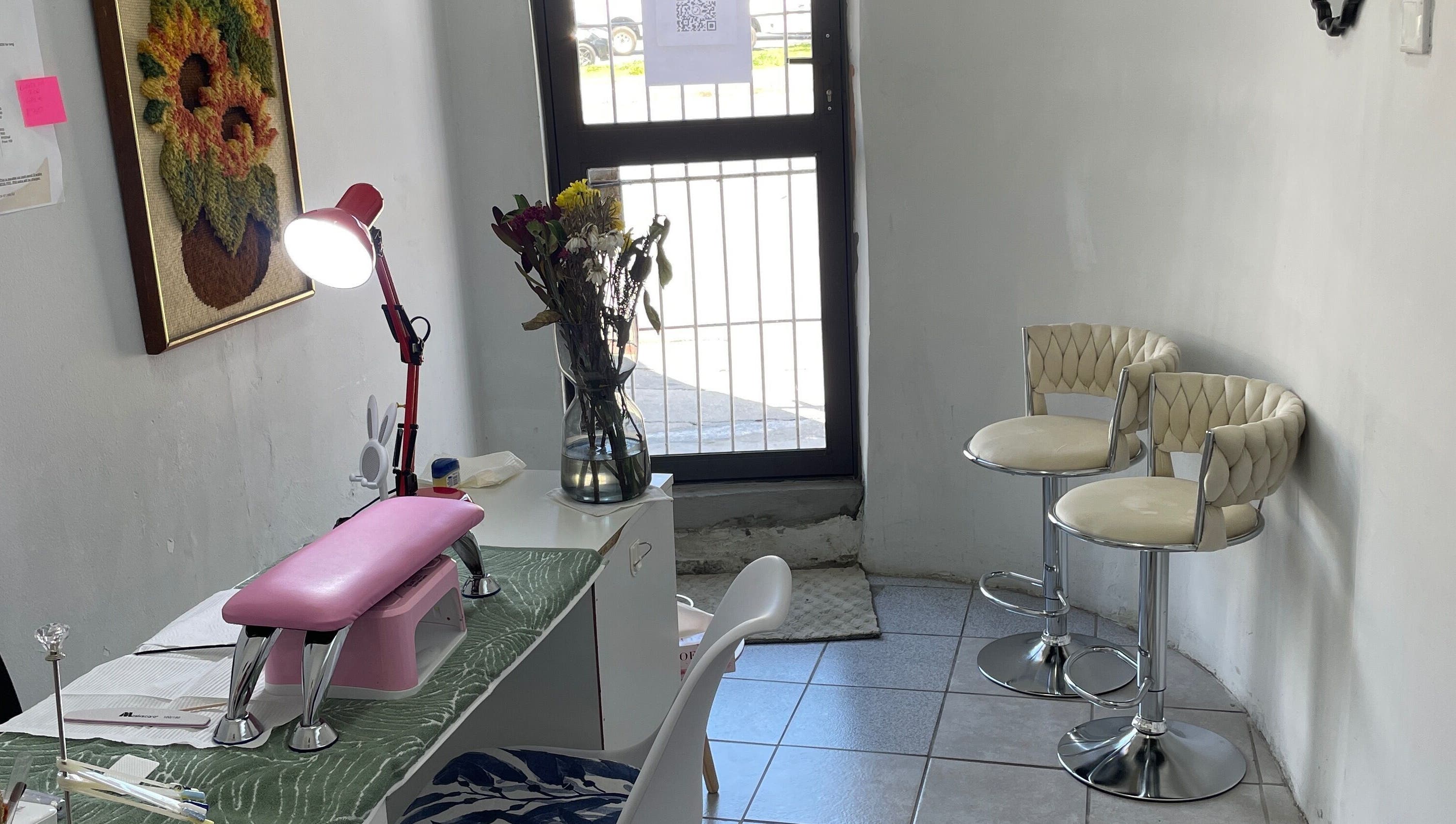 Nailed By Ndasi in Gqeberha offers a cozy nail space with modern seating and floral decor.