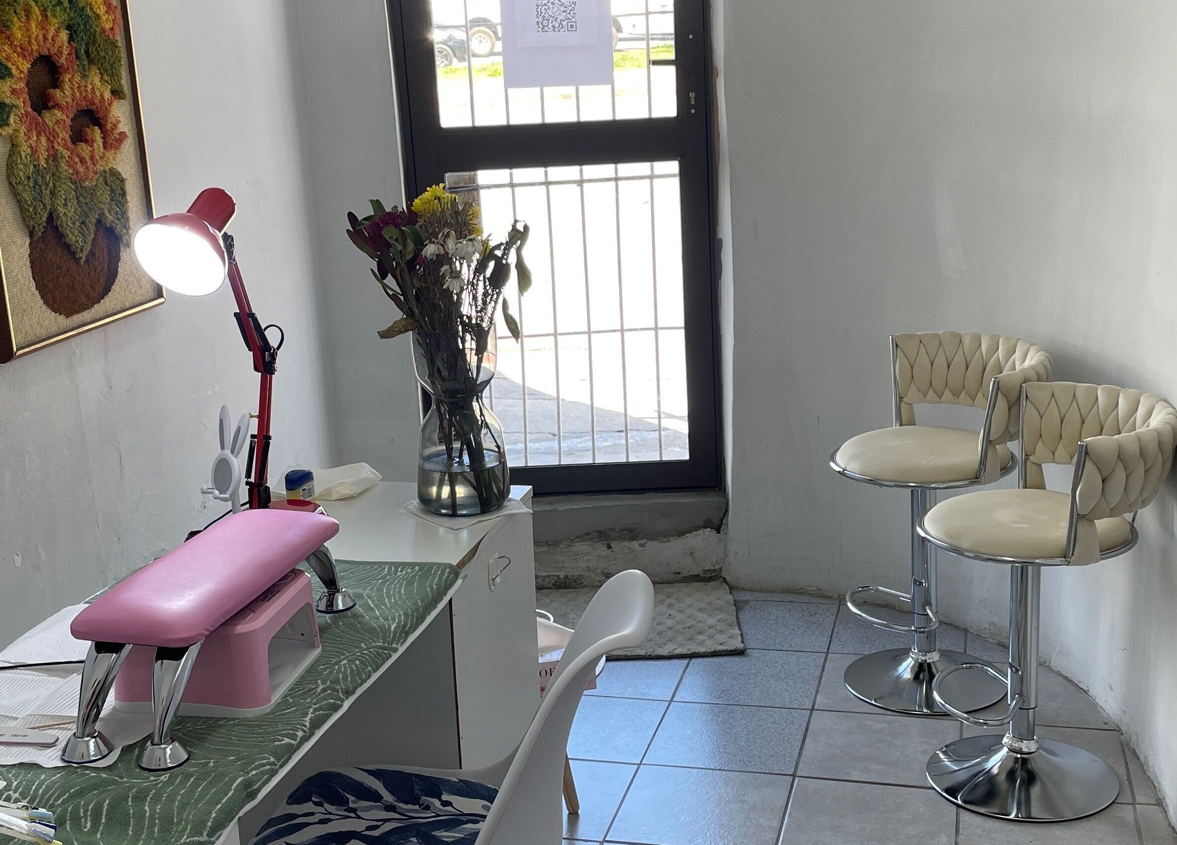 Nailed By Ndasi in Gqeberha offers a cozy nail space with modern seating and floral decor.