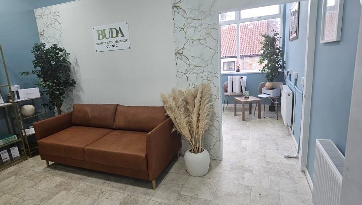 Relaxing lounge area at Buda Beauty, Shildon, England, featuring a brown sofa and elegant decor.