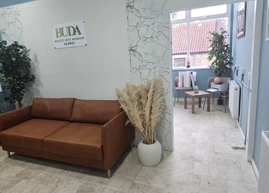 Relaxing lounge area at Buda Beauty, Shildon, England, featuring a brown sofa and elegant decor.