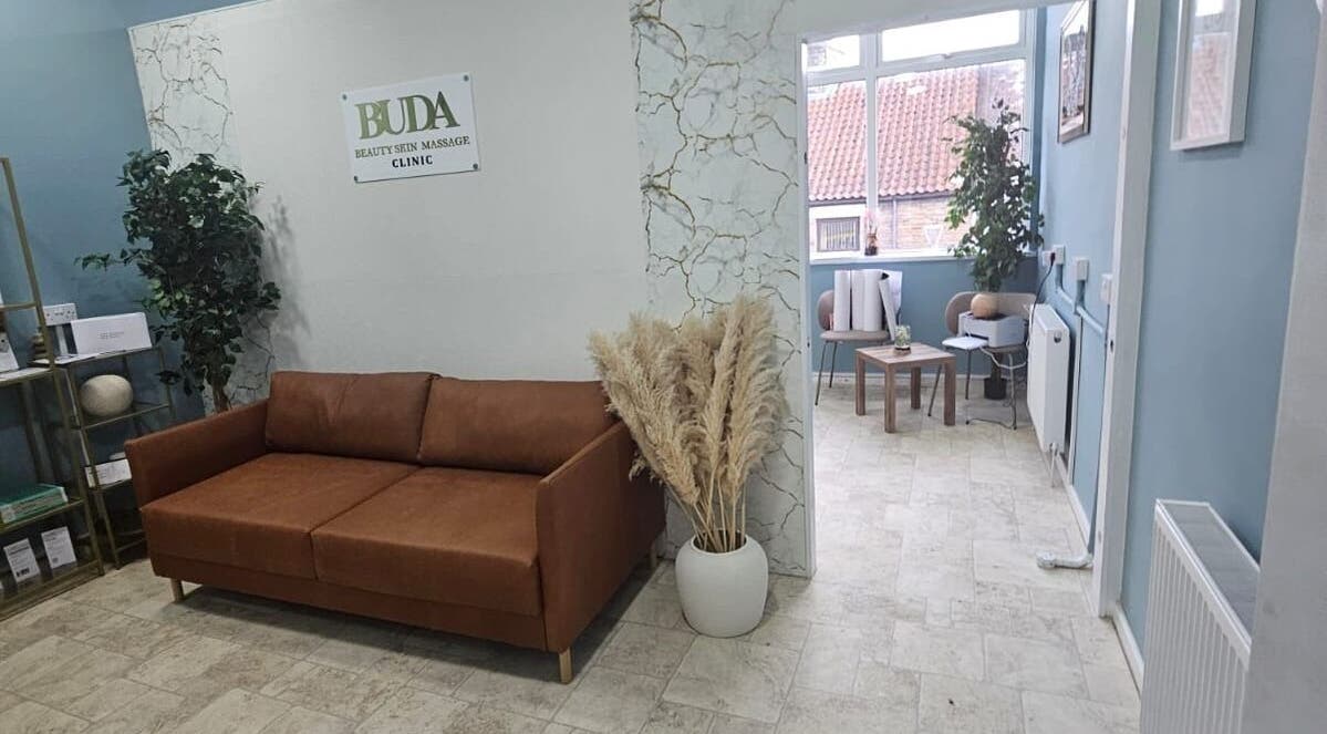 Inviting lounge area at Buda Beauty, Shildon, England, GB with cozy sofa and plants.