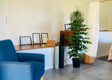 Cozy massage room at Kea Forest in Korora, New South Wales, AU, featuring a blue chair and wellness certificates.