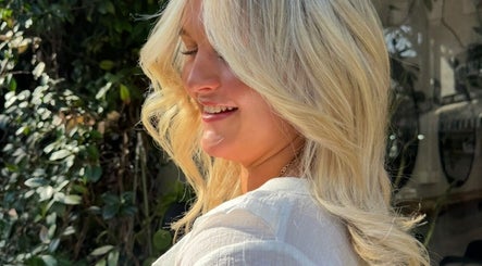 A smiling woman with styled hair enjoying a sunny day at Glen Alpine Beauty Hub, Glen Alpine, New South Wales, AU.