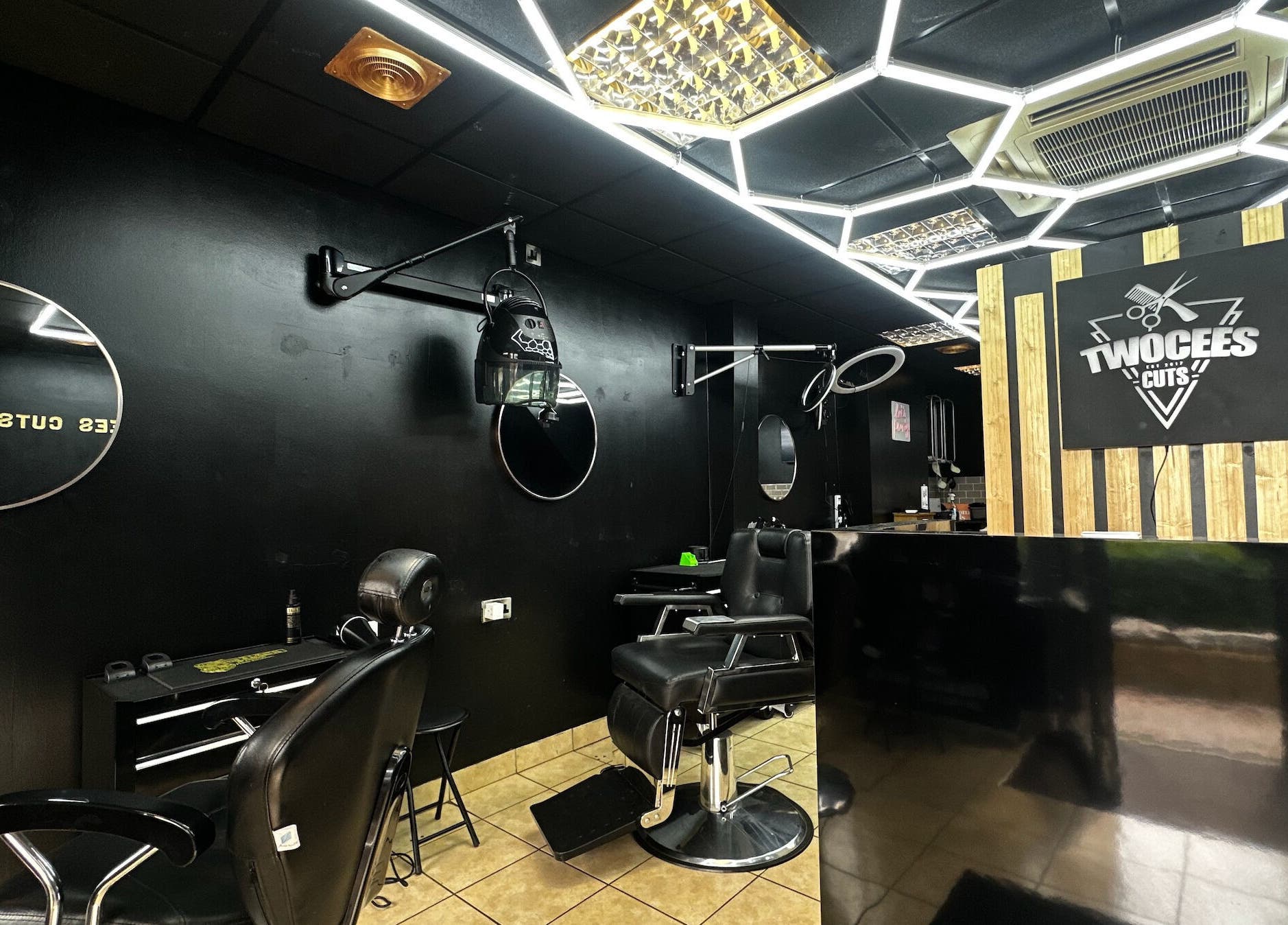Chic black interior of Twocees Cuts salon in Stoke-on-Trent, England, GB with stylish mirrors and chairs.