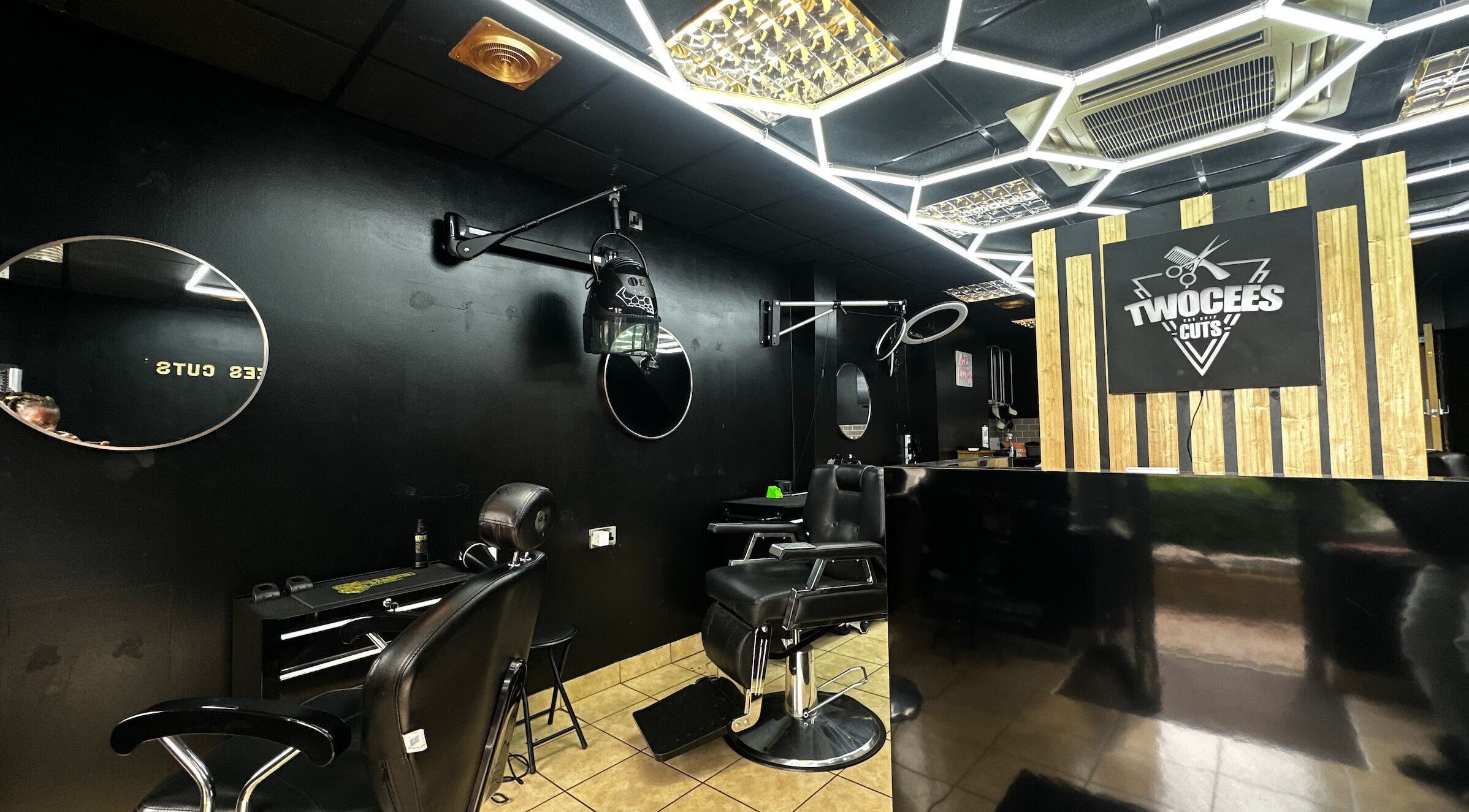 Chic black interior of Twocees Cuts salon in Stoke-on-Trent, England, GB with stylish mirrors and chairs.