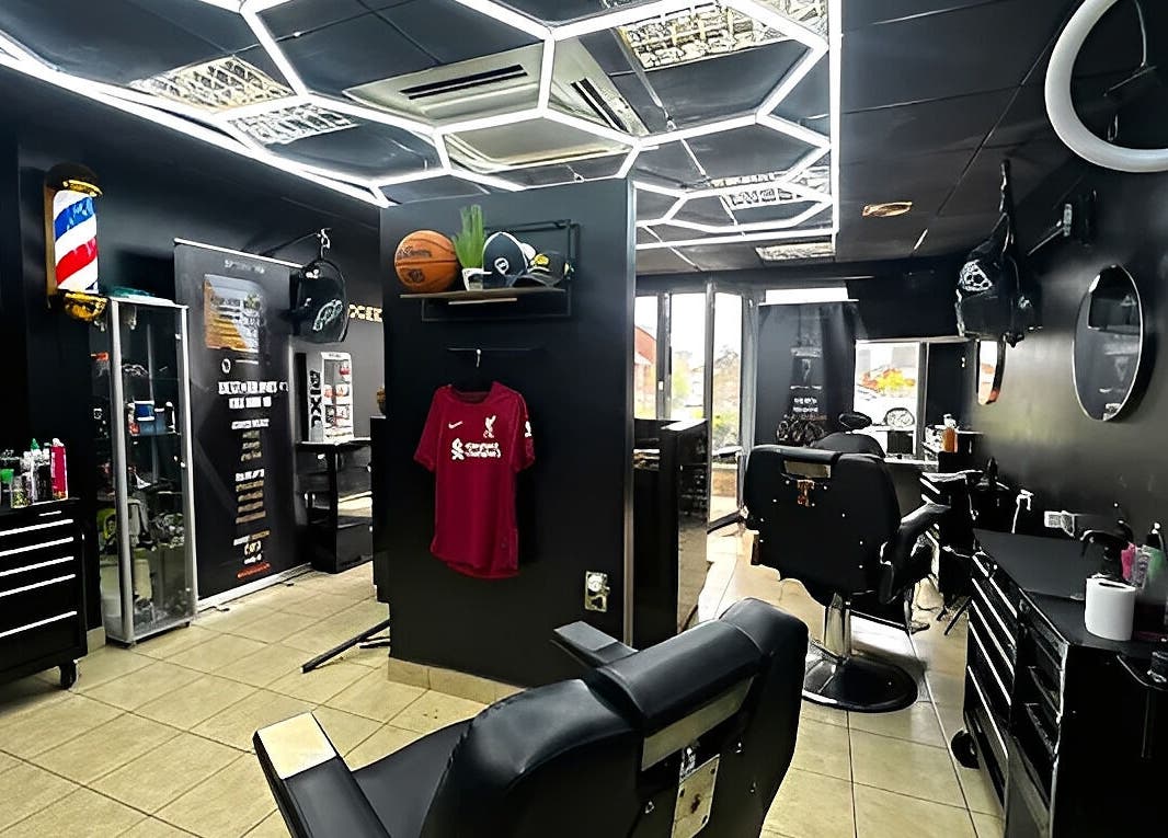 Modern interior of Twocees Cuts in Stoke-on-Trent, England, GB featuring sleek black decor and barber chairs.