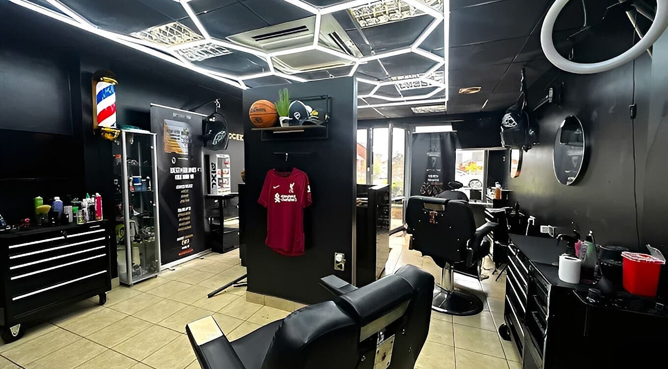 Modern interior of Twocees Cuts in Stoke-on-Trent, England, GB featuring sleek black decor and barber chairs.