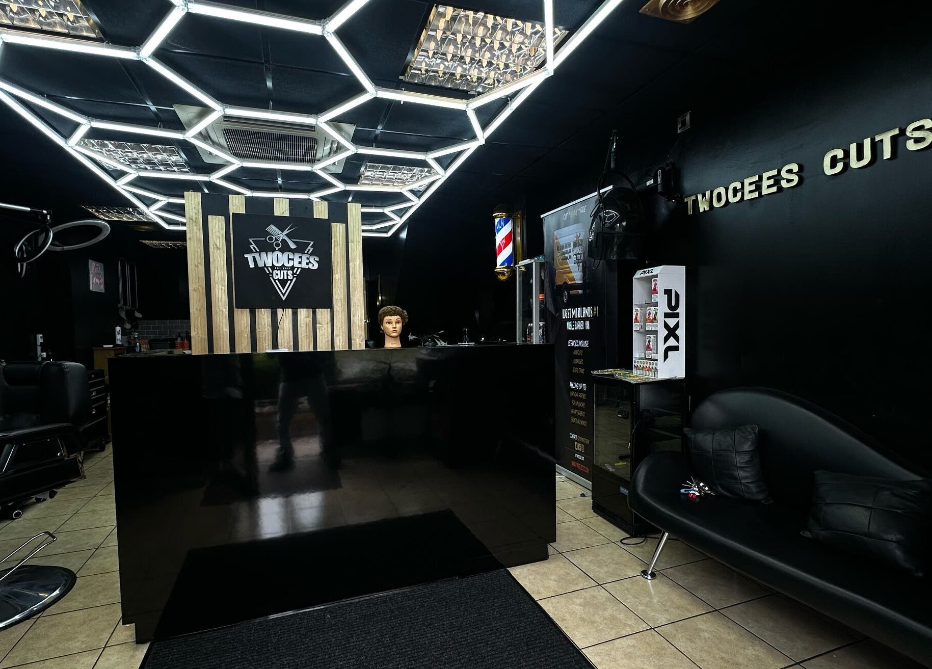 Modern interior of Twocees Cuts barbershop in Stoke-on-Trent, England, featuring sleek black decor.