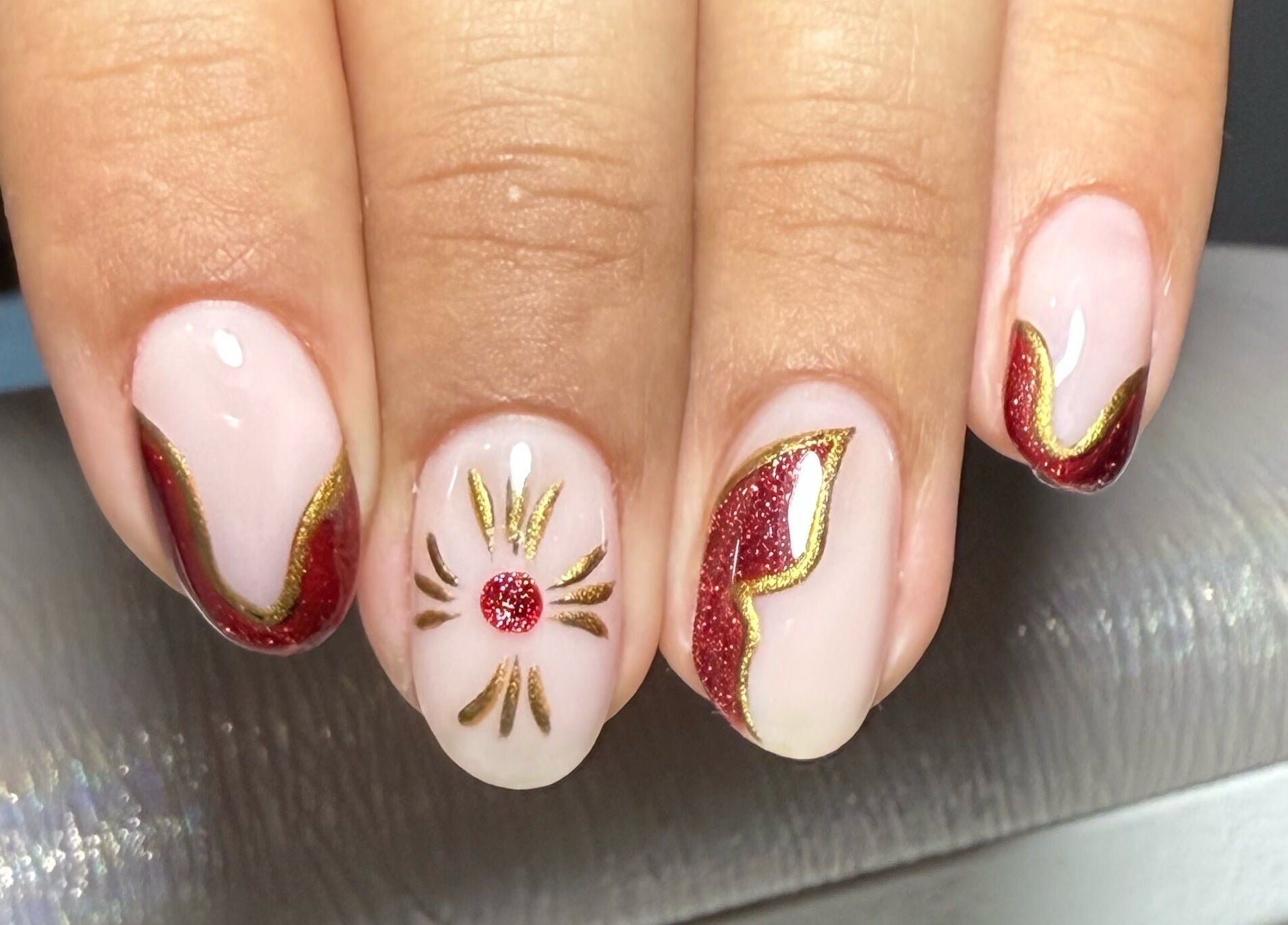 Diseño de uñas sofisticado con detalles dorados y rojos en Beanailsstudio, Buenos Aires, Ciudad Autónoma De Buenos Aires, AR.
